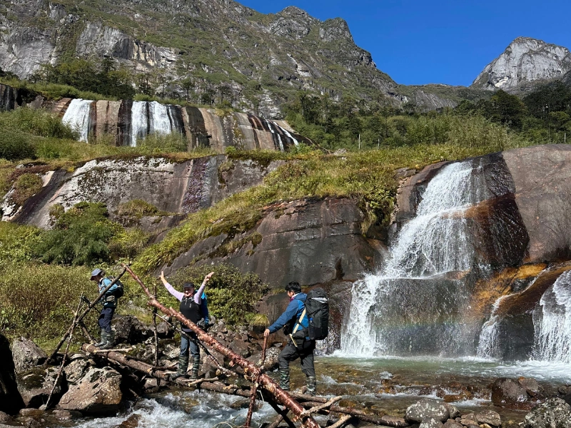 Trekkers below waterfalls in the eastern Himalayas