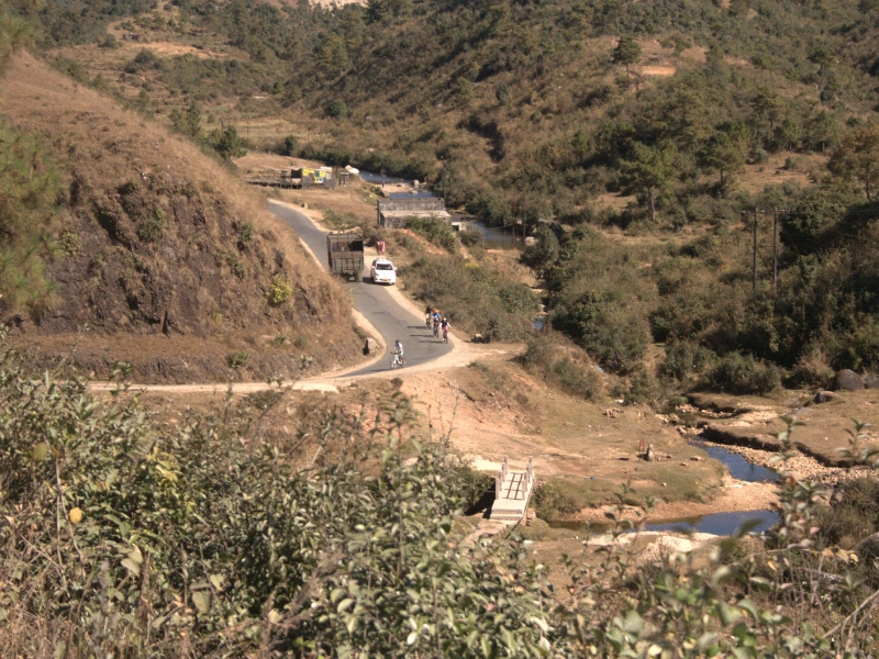 Cyclists riding a winding road through the hills of Meghalaya