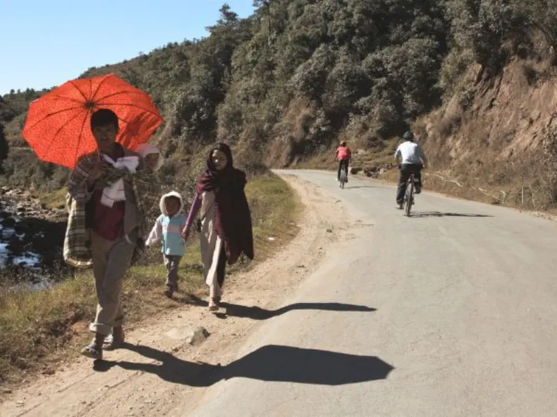 Cyclists passing local walkers on a Meghalaya road