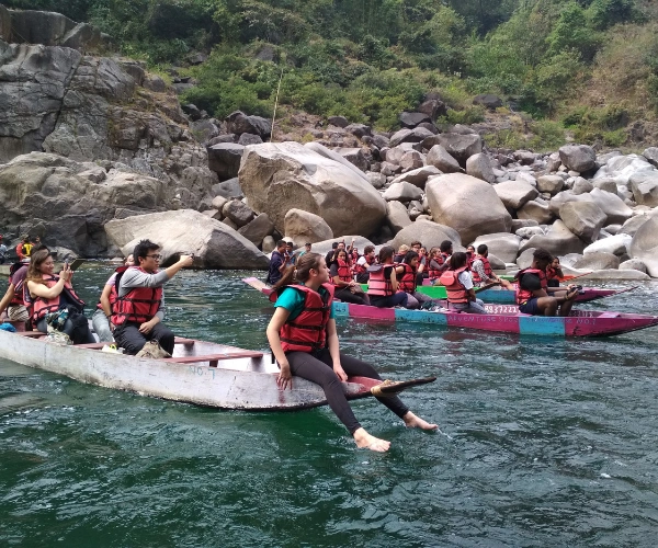 Youth expedition group boating through a rocky river landscape in Meghalaya