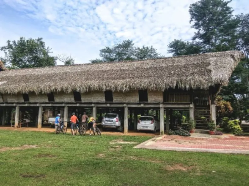 Cyclists near a traditional house in Upper Assam