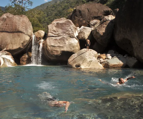 Swimming below a waterfall on a Meghalaya activity holiday
