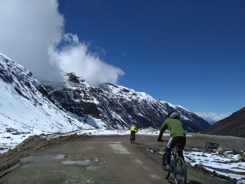Cyclists riding through snowy high roads of western Arunachal