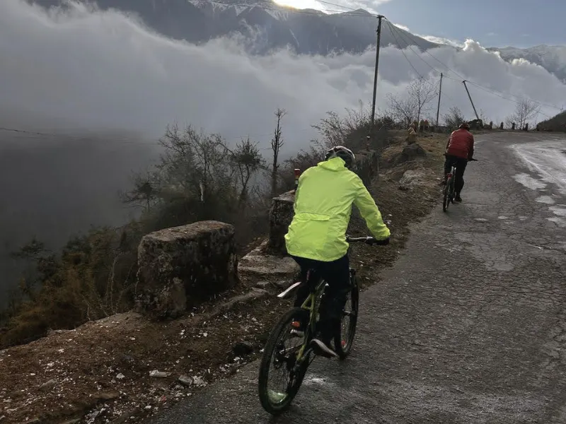 Cyclists riding above clouds on the road to Tawang
