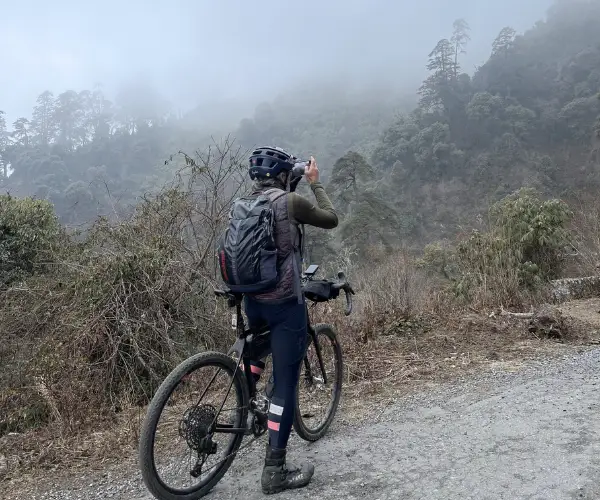 Cyclist pausing on the road to Tawang in misty mountain country