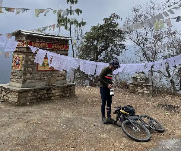 Cyclist resting near prayer flags on the Himalayan fixed departure route