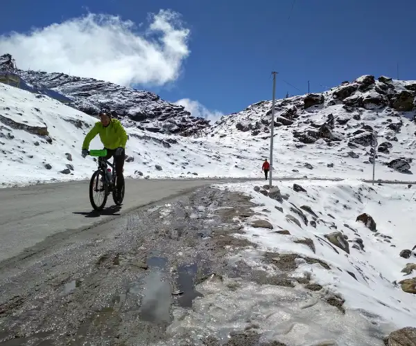 Cyclist riding through snowy high roads near Tawang