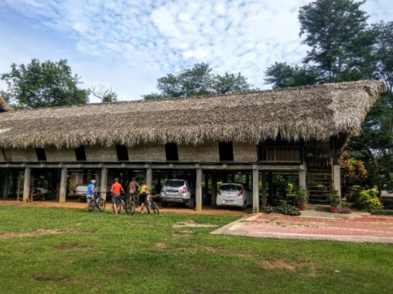 Cyclists outside a stilted traditional house in Eastern Arunachal Pradesh